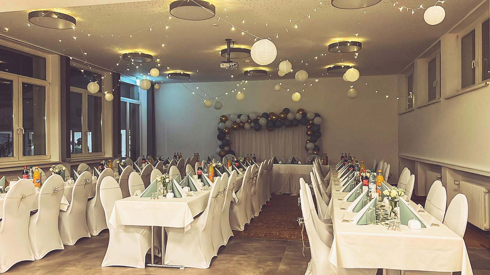 Weiße Stuhlhussen im Dorfgemeinschaftshaus Edesheim in Northeim bei einer Feier – elegante Dekoration für Hochzeiten und besondere Veranstaltungen