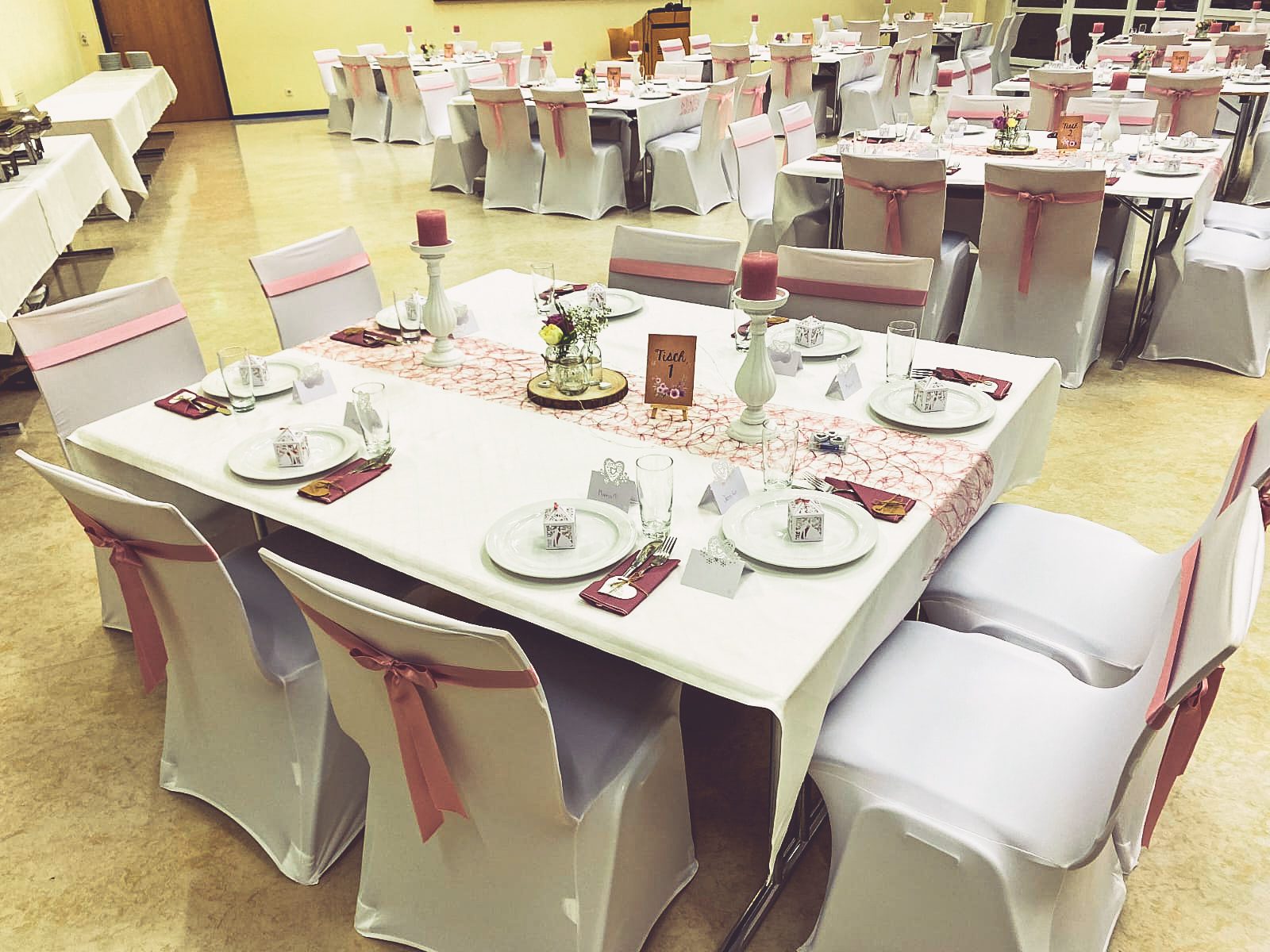 Stuhlhussen Klosterwaldhalle Pohlheim Weiße Stuhlhussen in der Klosterwaldhalle in Pohlheim bei einer Feier – elegante Dekoration für Hochzeiten und besondere Veranstaltungen