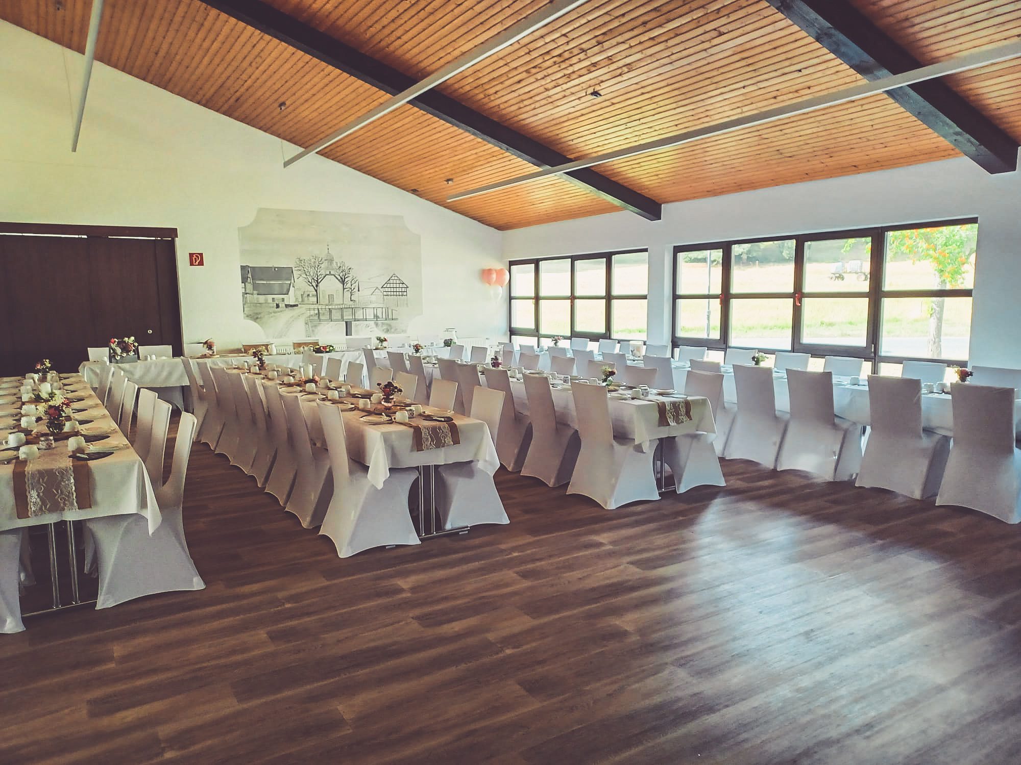 Weiße Stuhlhussen im Dorfgemeinschaftshaus Bergheim in Ortenberg bei einer Feier – elegante Dekoration für Hochzeiten und besondere Veranstaltungen