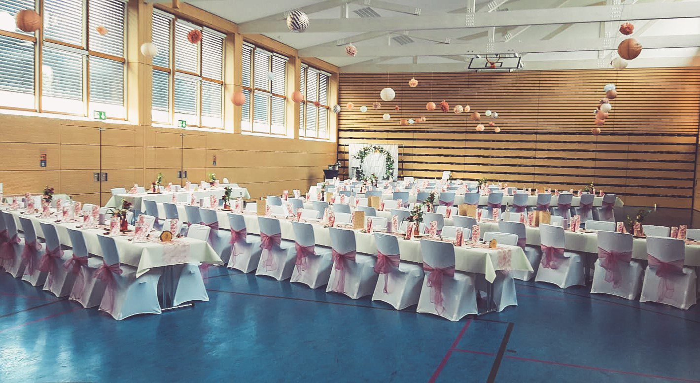 Weiße Stuhlhussen in der Sampo-Halle Bingenheim in Echzell bei einer Feier – elegante Dekoration für Hochzeiten und besondere Veranstaltungen