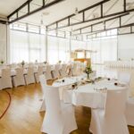 Weiße Stuhlhussen in der Goldbach Halle in Undenheim bei einer Feier – elegante Dekoration für Hochzeiten und besondere Veranstaltungen
