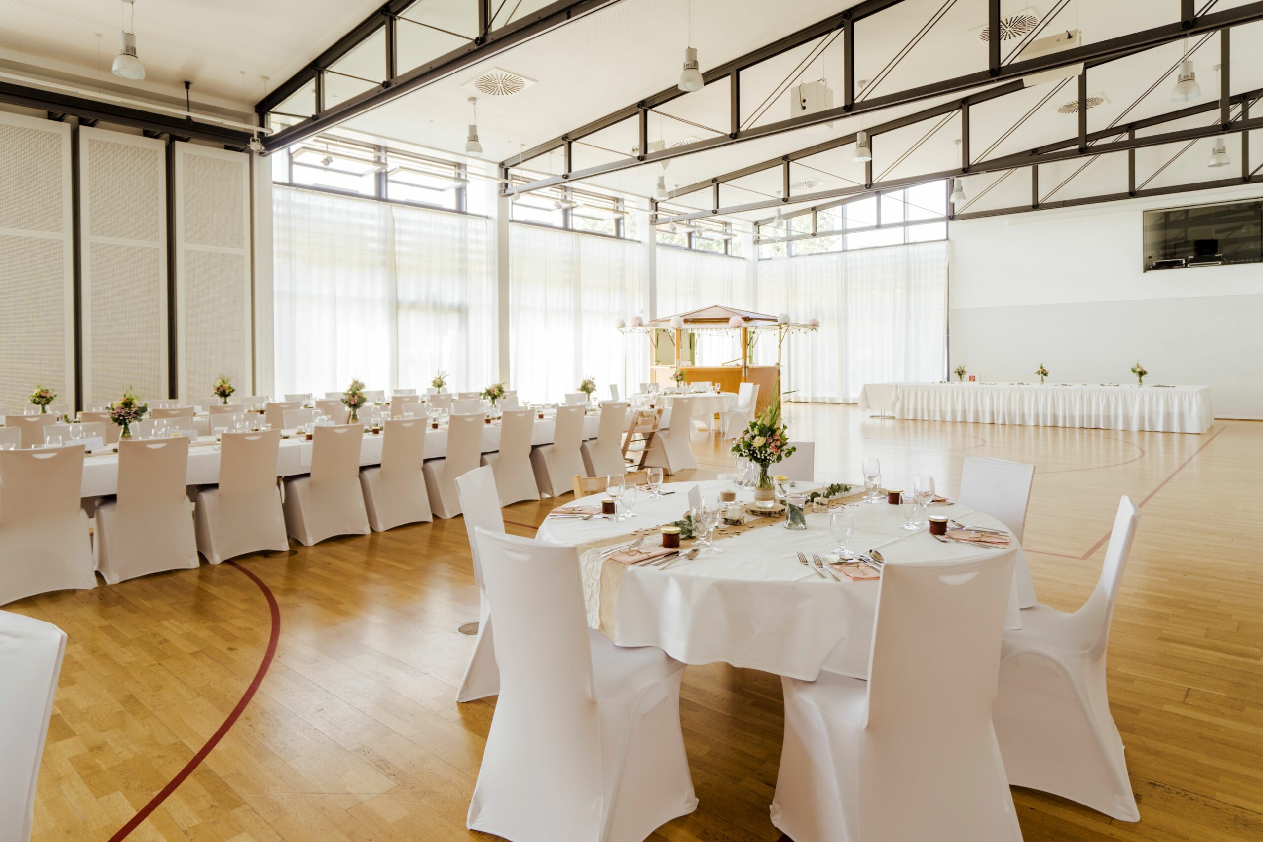 Weiße Stuhlhussen in der Goldbach Halle in Undenheim bei einer Feier – elegante Dekoration für Hochzeiten und besondere Veranstaltungen