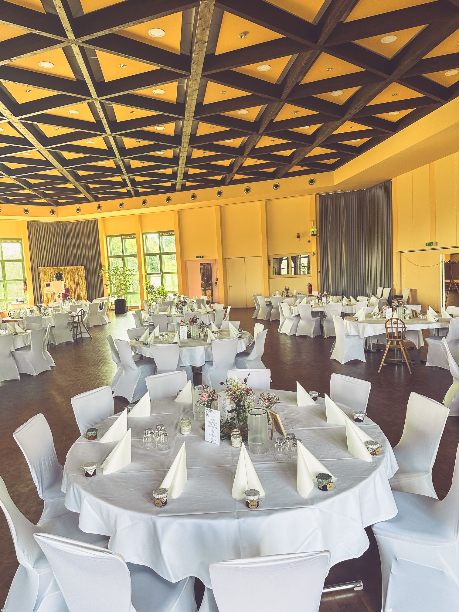 Stuhlhussen Klosterberghalle Langenselbold Weiße Stuhlhussen in der Klosterberghalle in Langenselbold bei einer Feier – elegante Dekoration für Hochzeiten und besondere Veranstaltungen