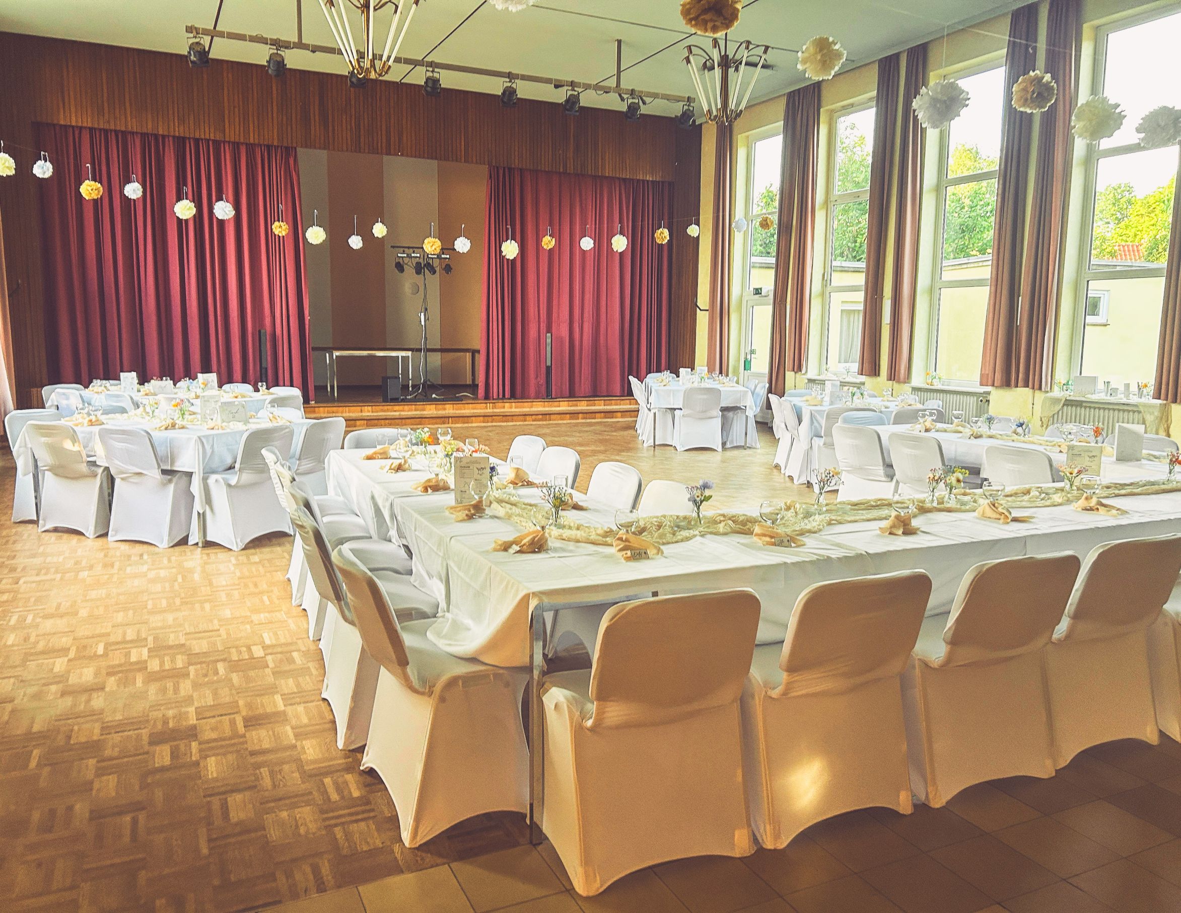 Weiße Stuhlhussen im Gemeinschaftshaus Karlshof e.V. in Lübeck bei einer Feier – elegante Dekoration für Hochzeiten und besondere Veranstaltungen